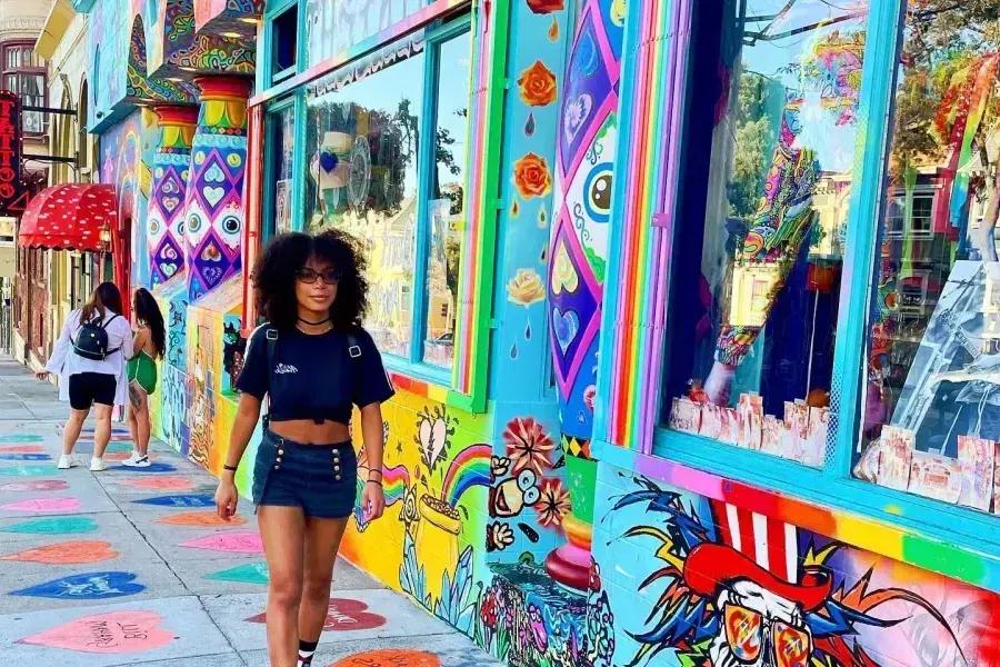 Una donna cammina lungo una strada con edifici colorati nel quartiere Haight-Ashbury di San Francisco.