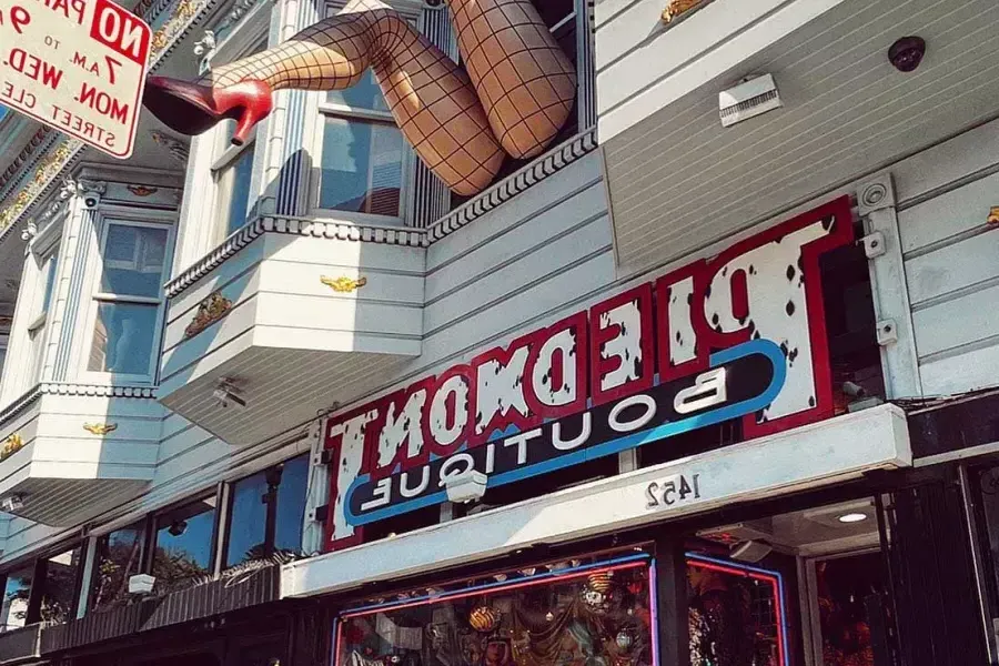 A pair of mannequin legs wearing fishnet stockings hang out of a window over Haight Street at Piedmont Boutique. 加州贝博体彩app.